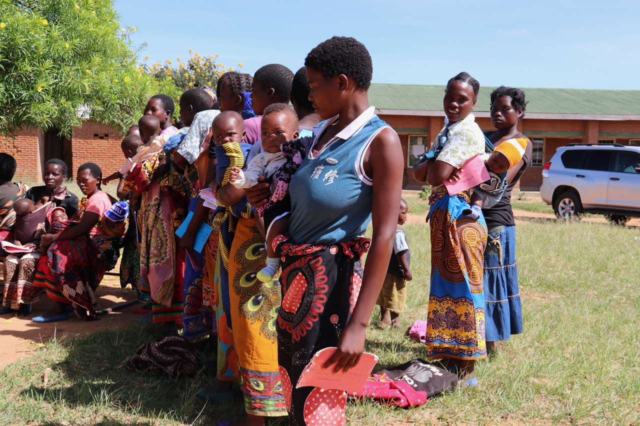 Mothers line-up and wait for their children to receive the RTS,S malaria vaccine, Mkaka Primary School Outreach, Malawi