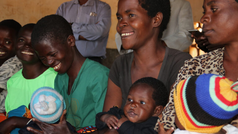 Mothers wait for their five-month old children to receive the first dose of the malaria vaccine