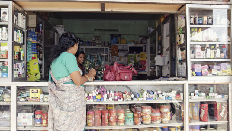 An Indian woman paying at the counter of a pharmacy-drugstore along the road in Cherthala, Kerala, India