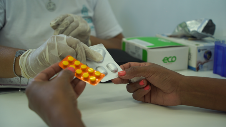 A healthcare worker hands a patient two pill packets